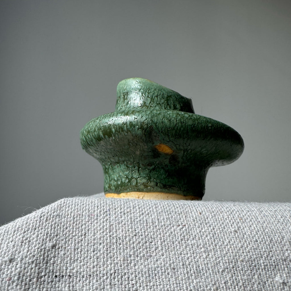 Green ceramic vase on a gray surface with a gray background