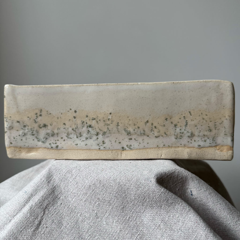 Rectangular stone object with a textured surface on a gray background