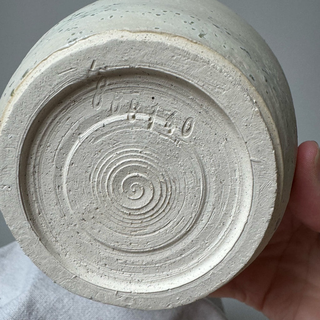 Close-up of a textured ceramic vase with spiral design on a gray background