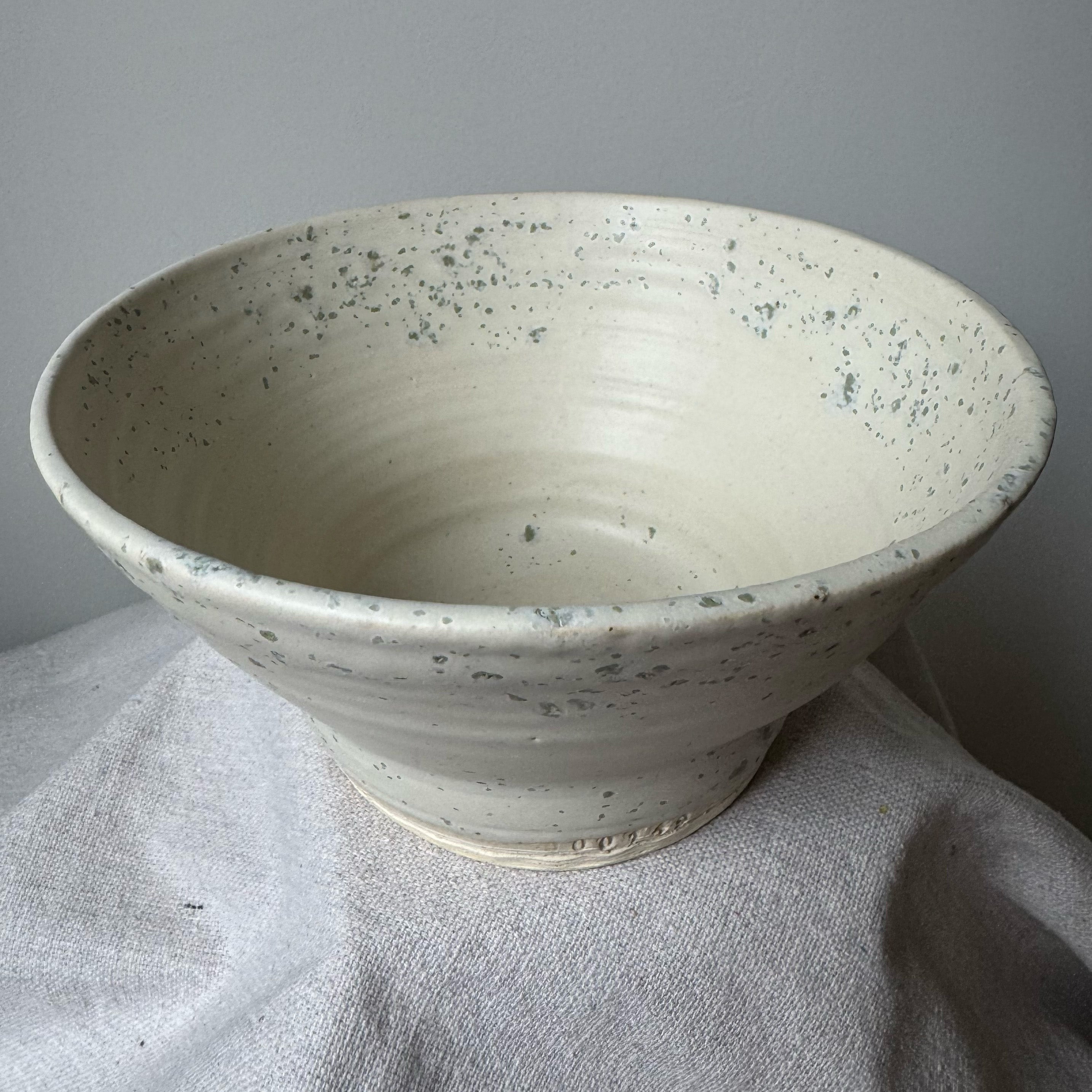 Speckled ceramic bowl on a textured surface with a neutral background
