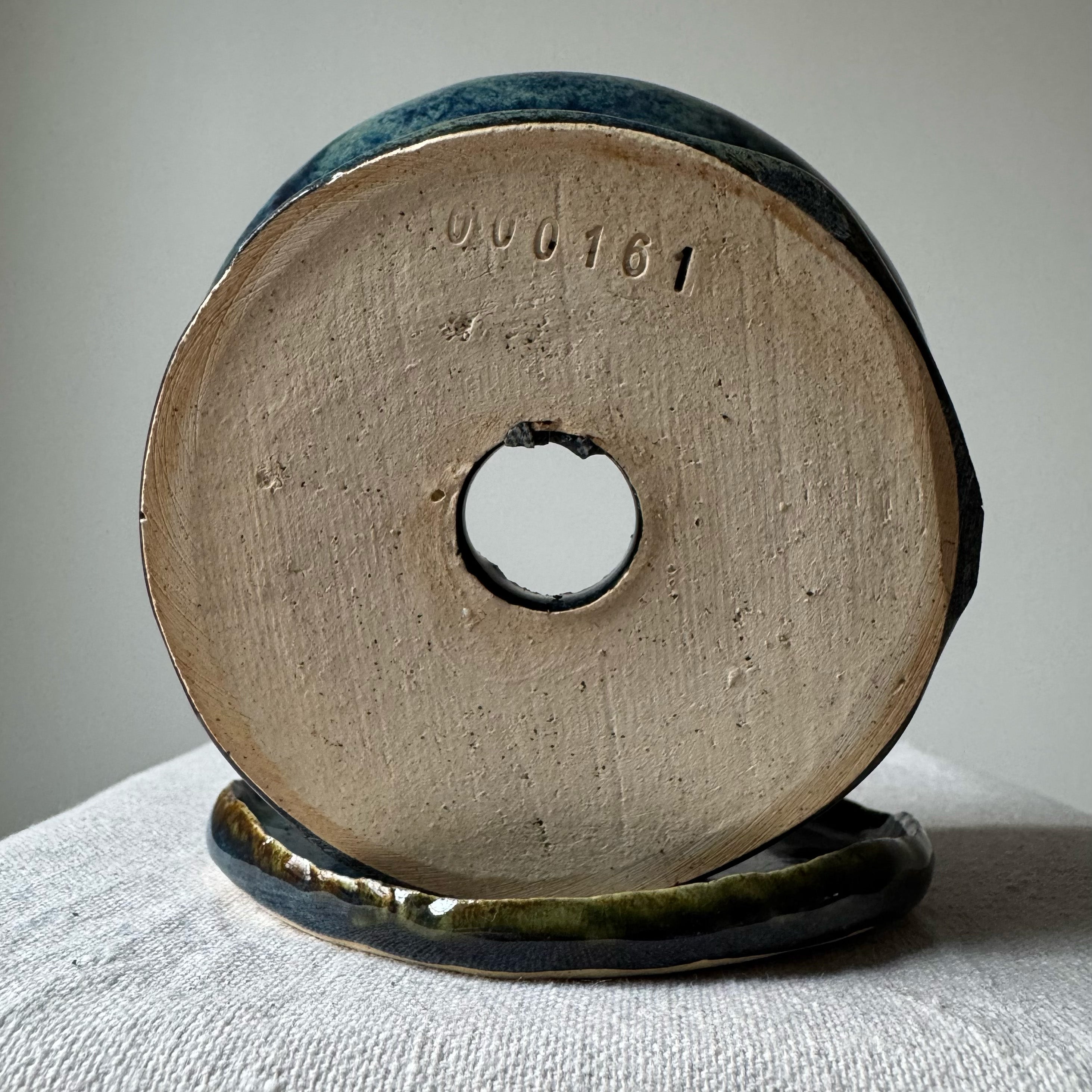 Ceramic spool with a central hole on a textured surface