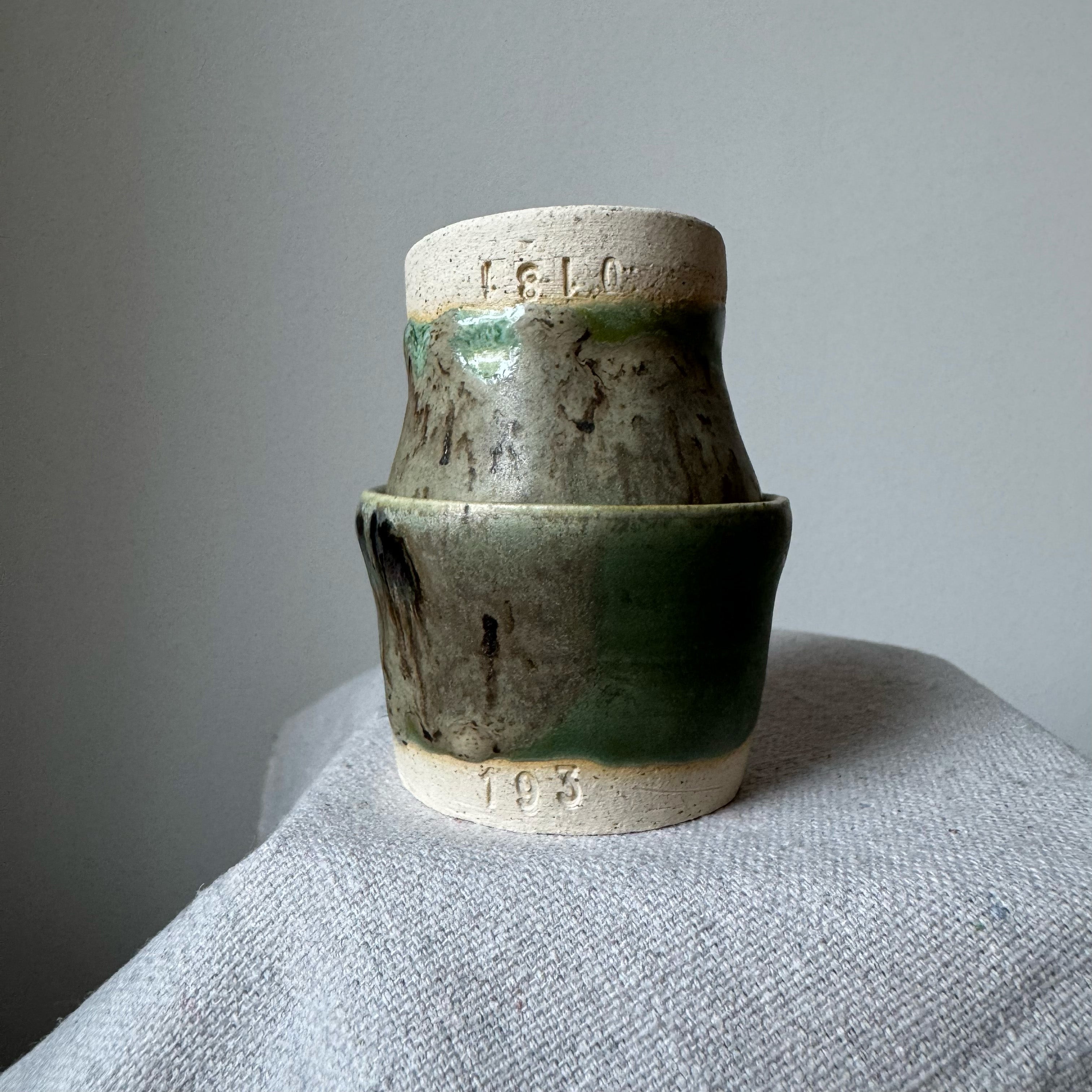 Stack of ceramic pots with green glaze on a gray surface