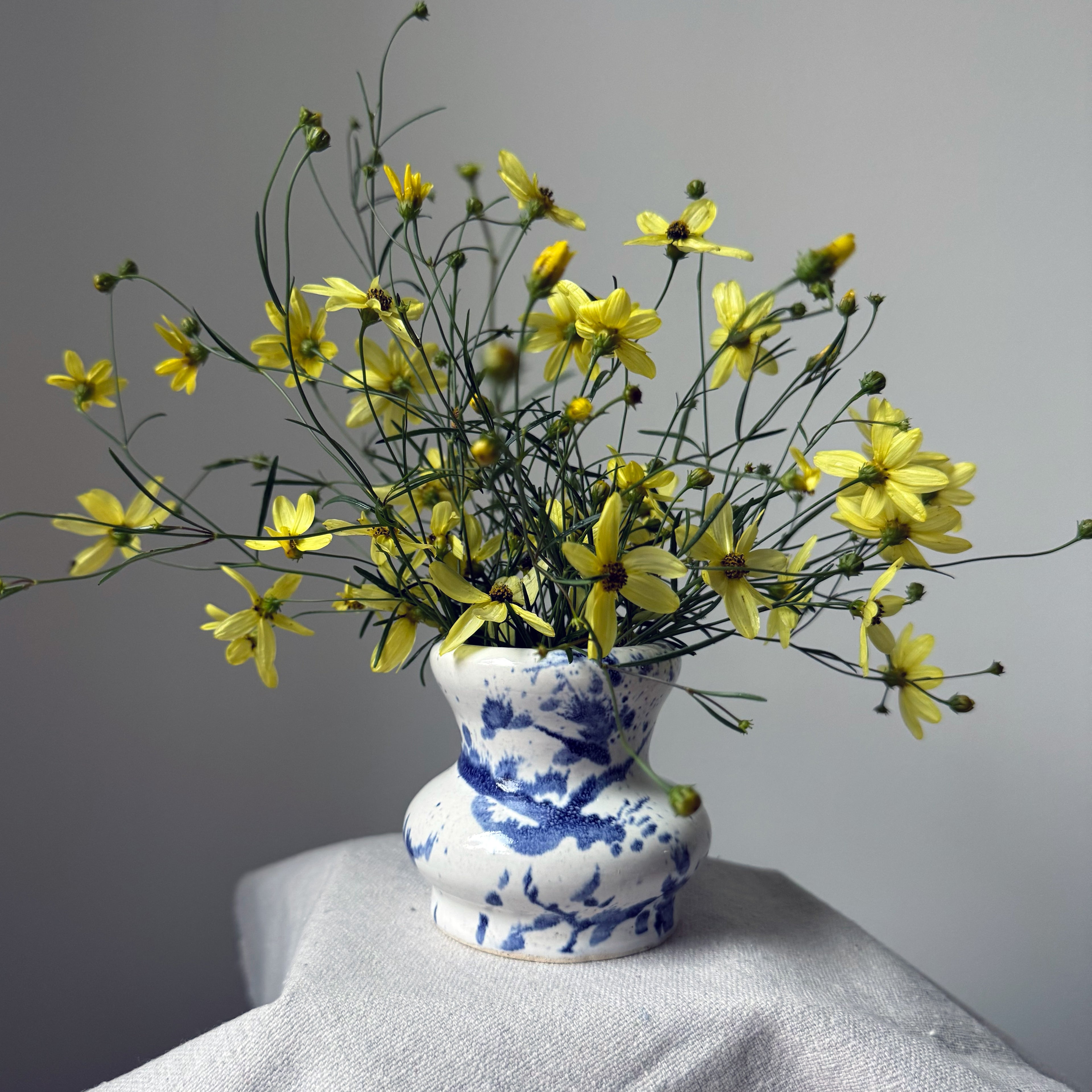 Vase with yellow flowers on a gray surface against a gray background