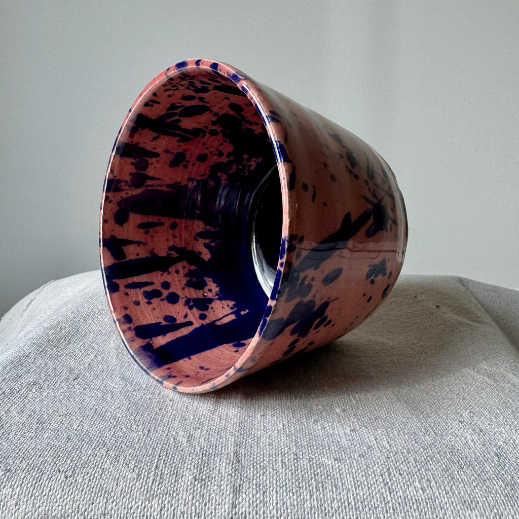 Cylindrical container with pink and blue abstract pattern on a gray surface