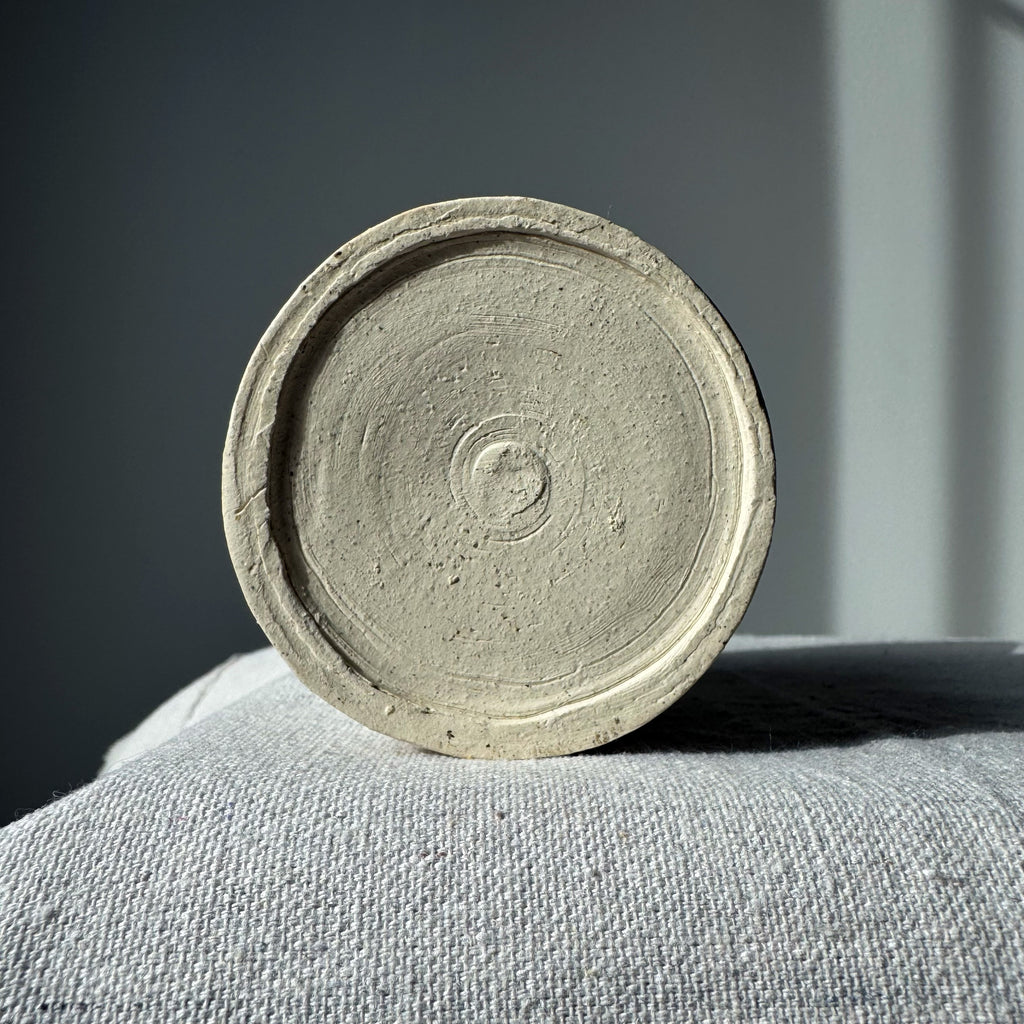 Round concrete coaster on a gray surface with a neutral background
