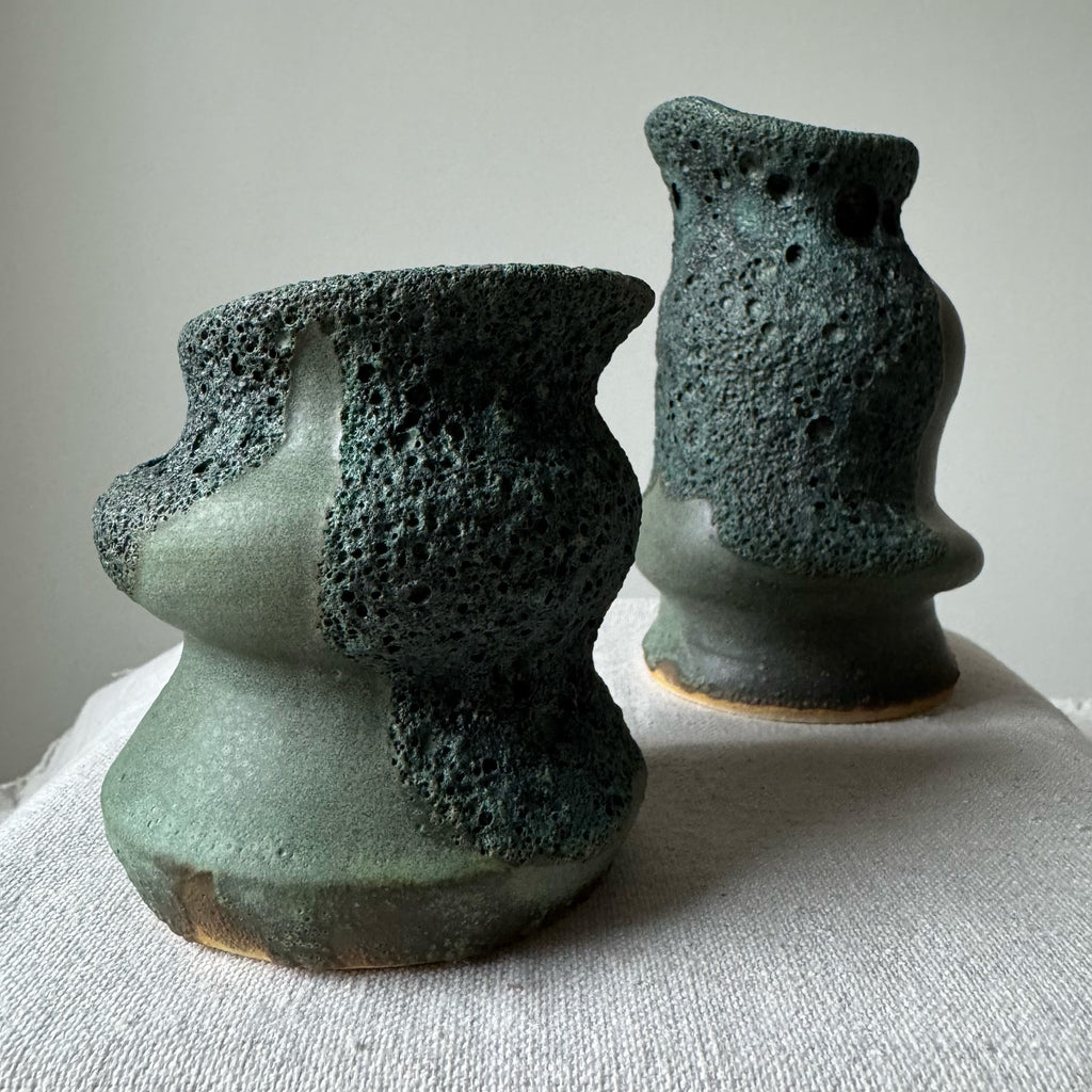 Two textured ceramic vases on a light fabric surface with a neutral background