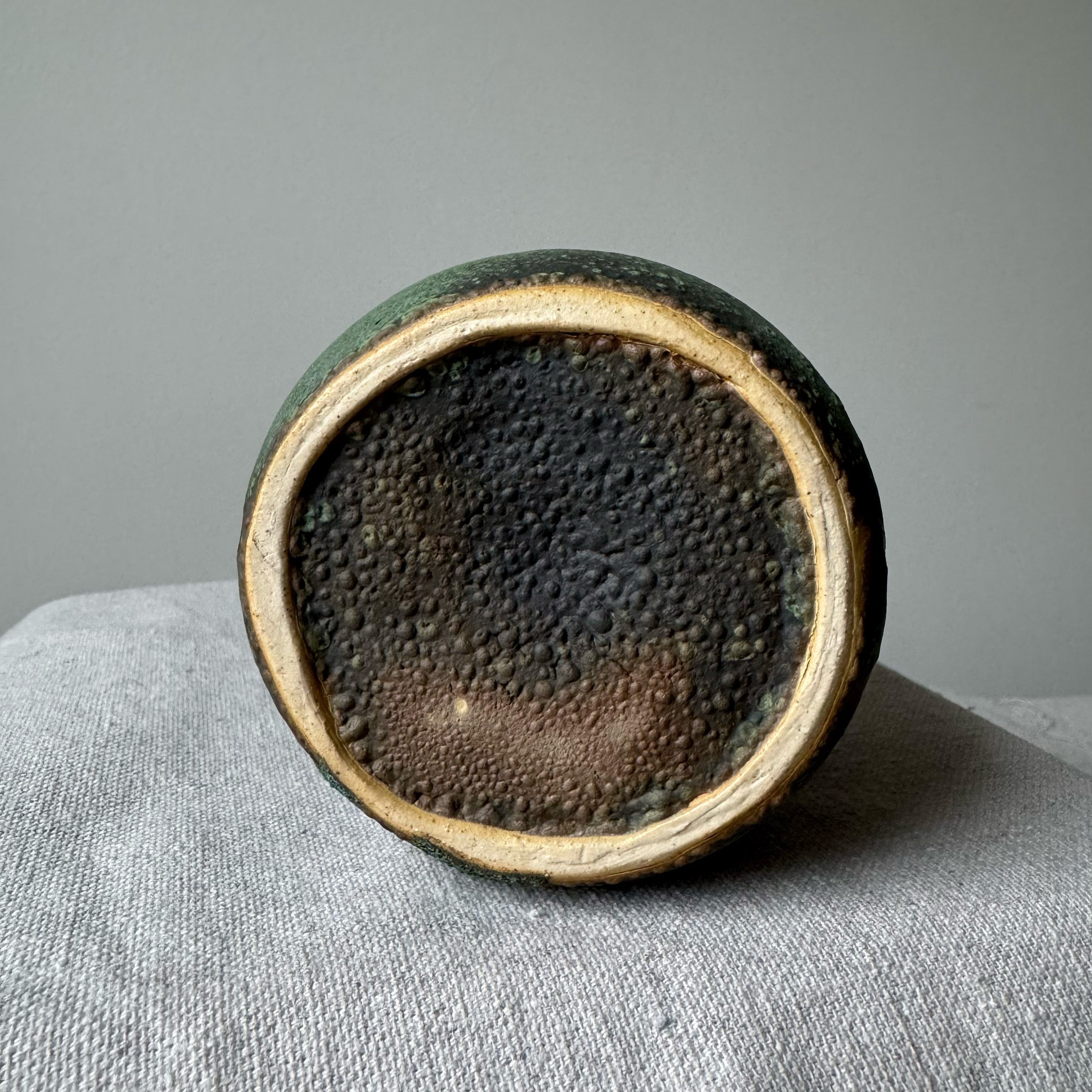 Ceramic container with textured surface on a gray fabric background