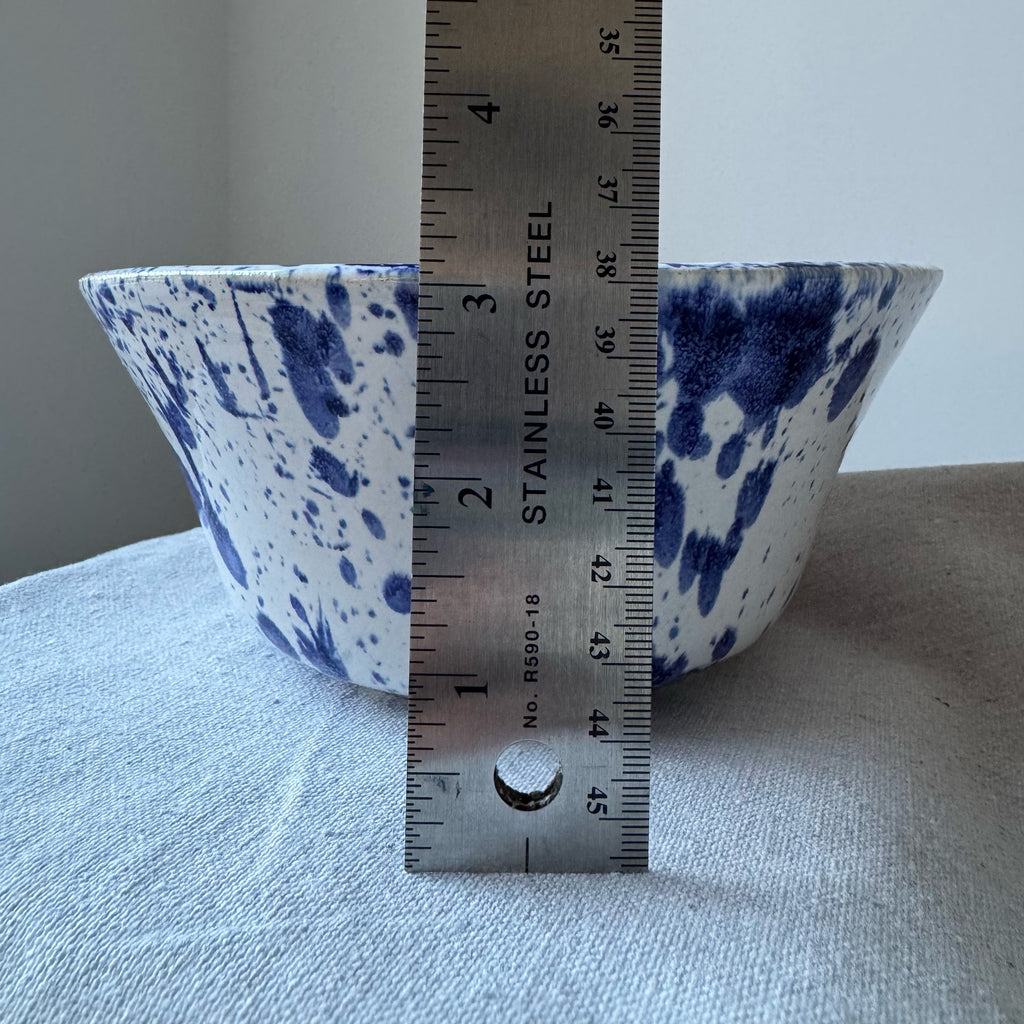 Blue and white ceramic bowl with a ruler for scale on a gray surface