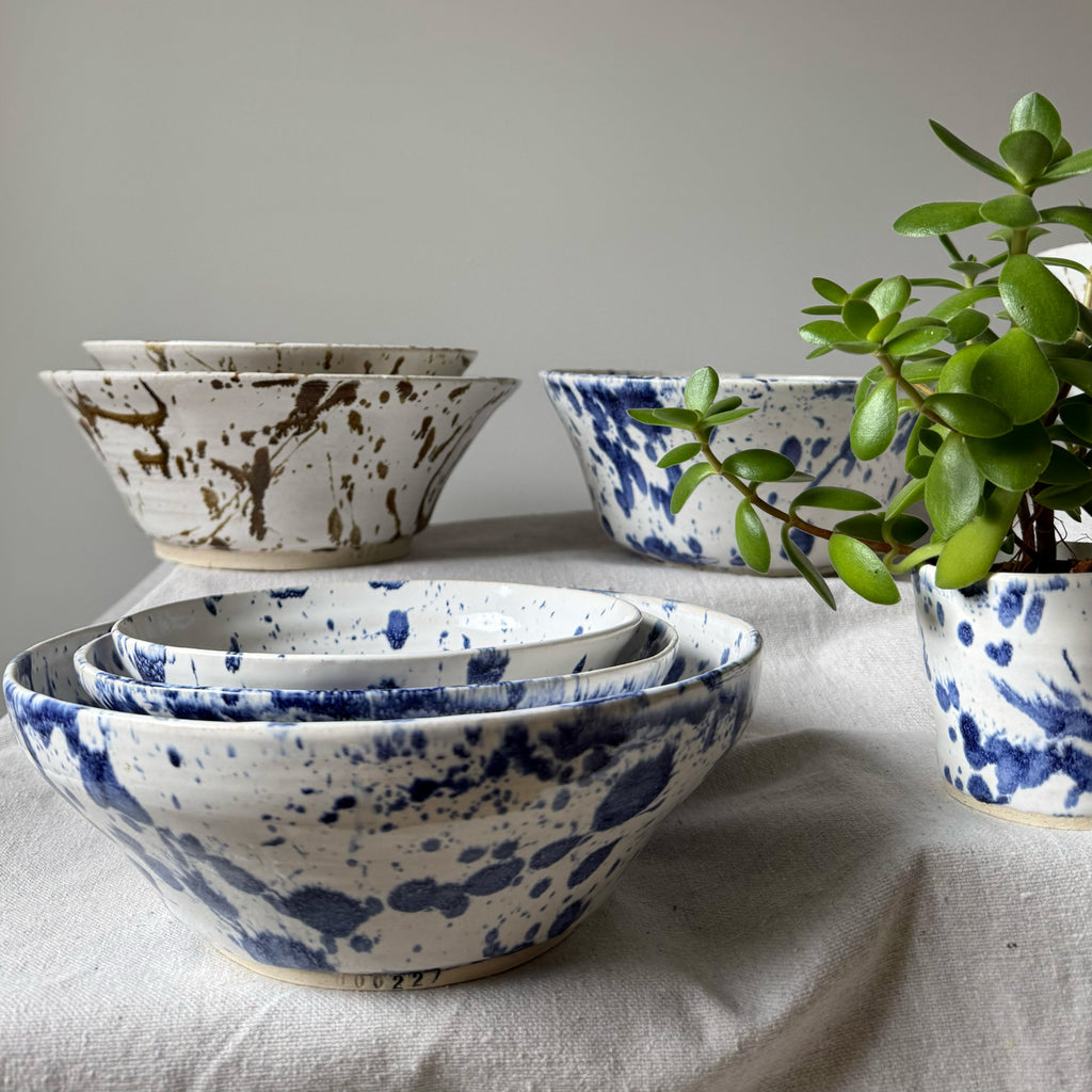 Set of ceramic bowls with blue and white speckled pattern on a neutral background