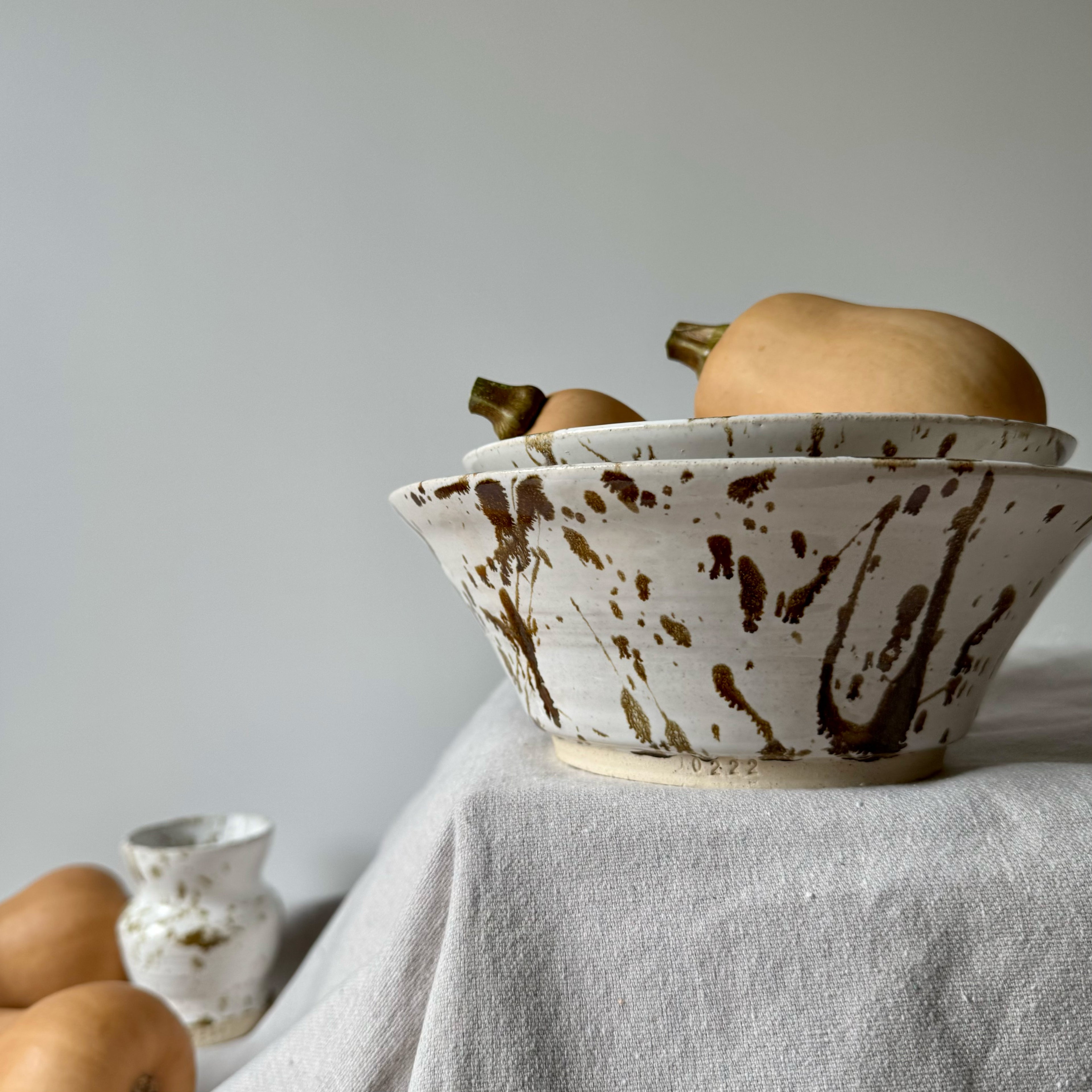Ceramic bowl with brown speckles on a light gray surface with a neutral background