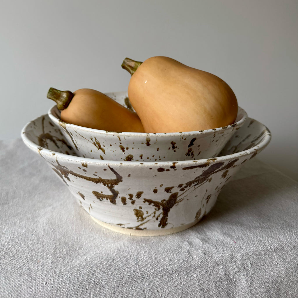 Ceramic bowls with speckled brown design on a white surface with butternut squash.