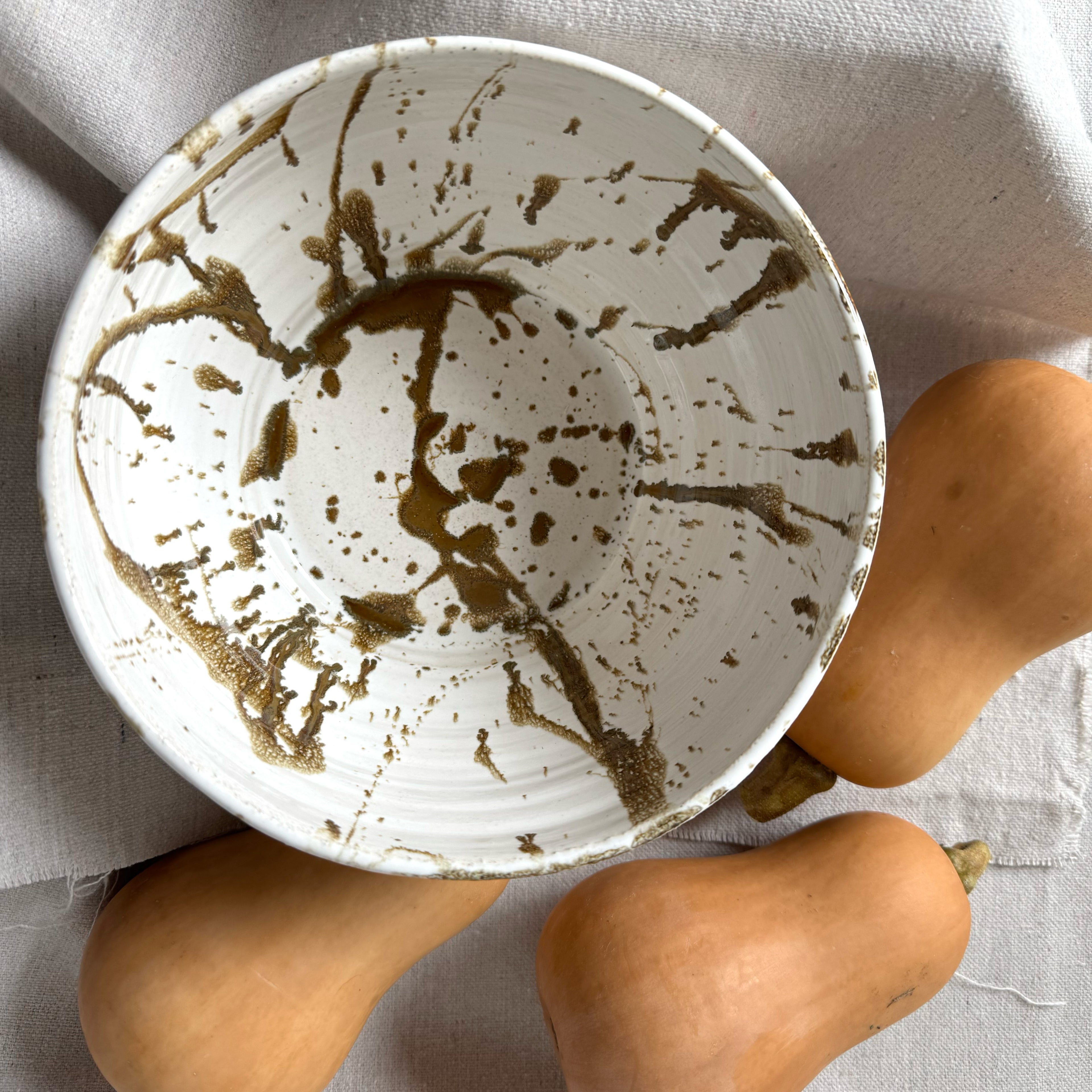 White ceramic bowl with brown abstract design on a light gray background with butternut squash.