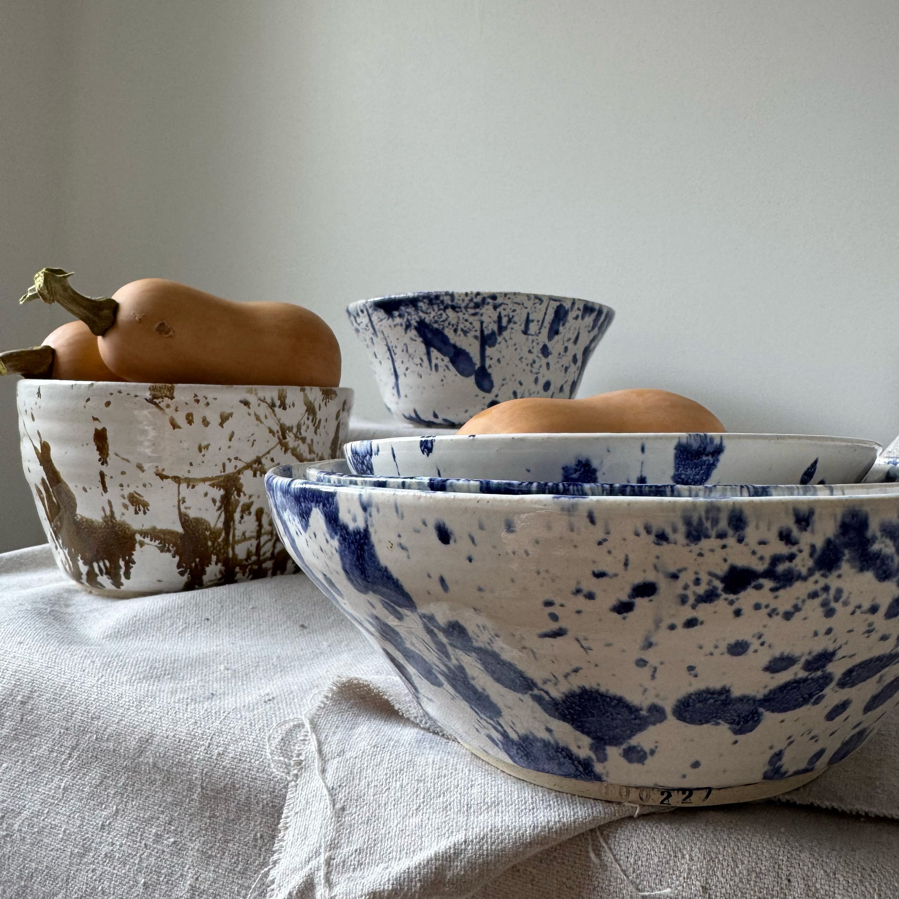 Ceramic bowls with blue and white speckled pattern on a light surface.