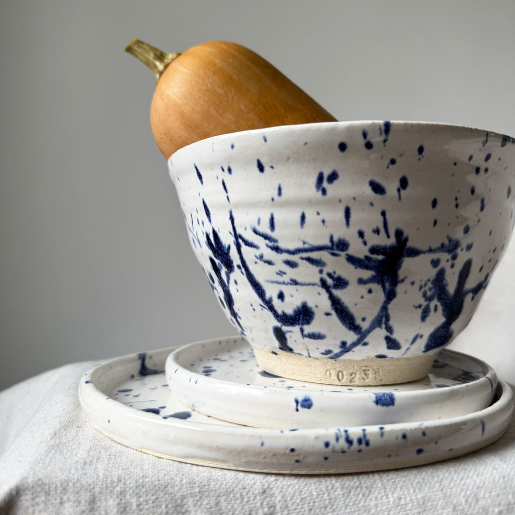 Speckled blue and white ceramic bowl with a pumpkin on a neutral background