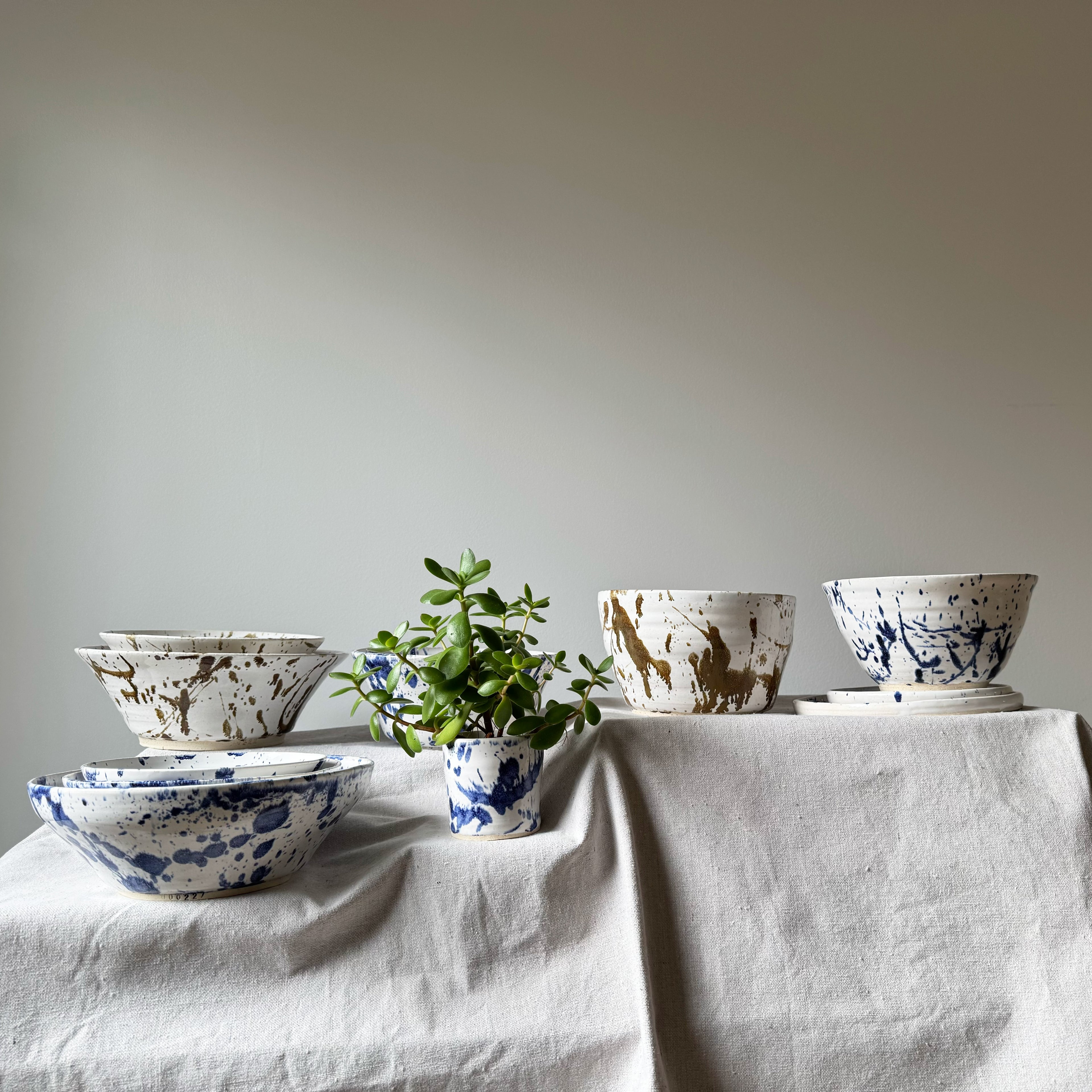 Set of ceramic bowls with abstract patterns on a white tablecloth against a plain background