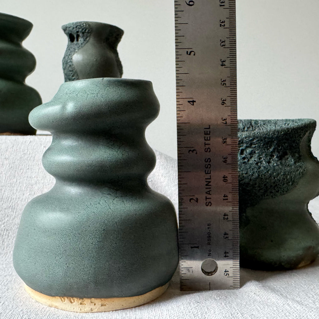 Green ceramic vase with a ruler for scale on a light background