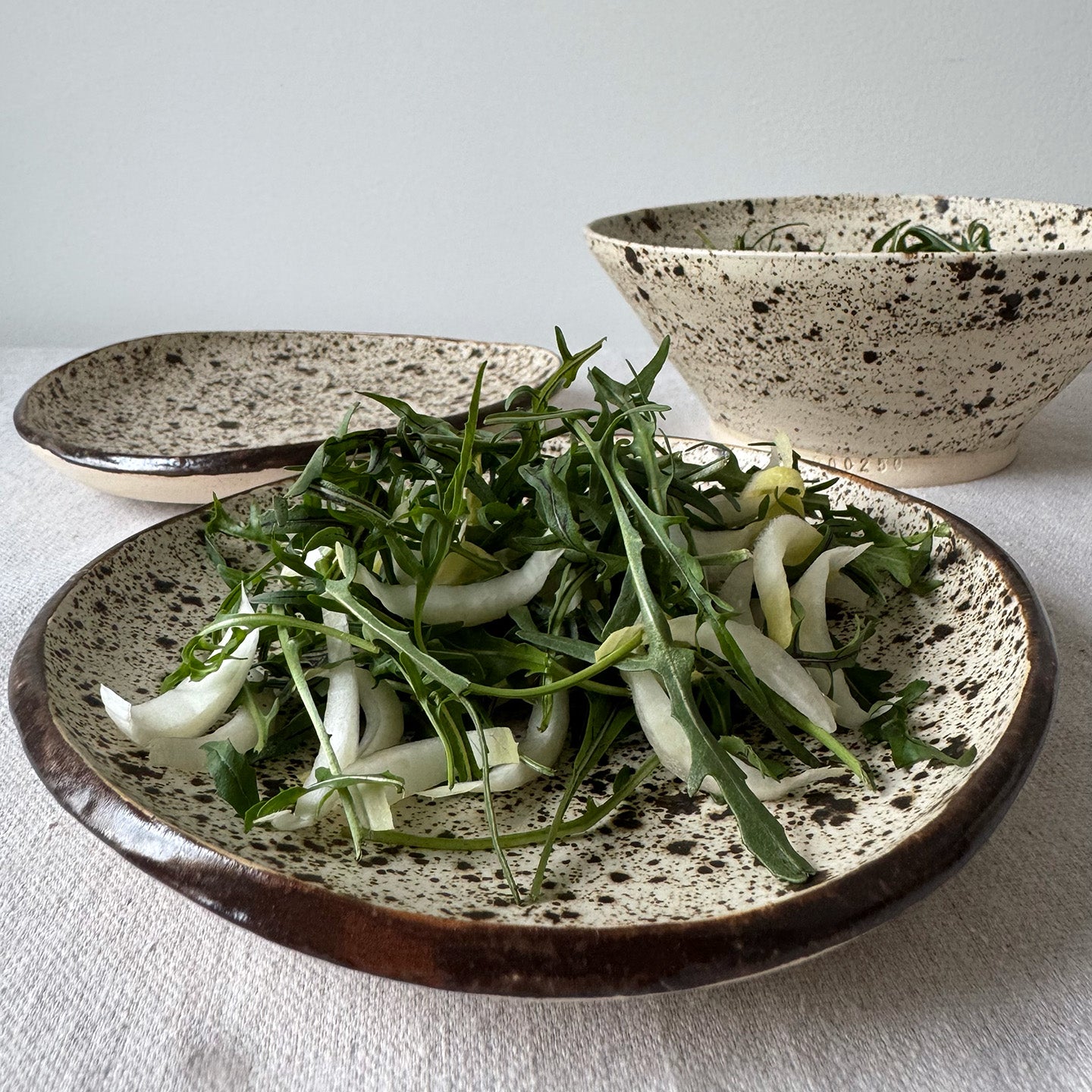 Spotted ceramic plates with green salad on a light background