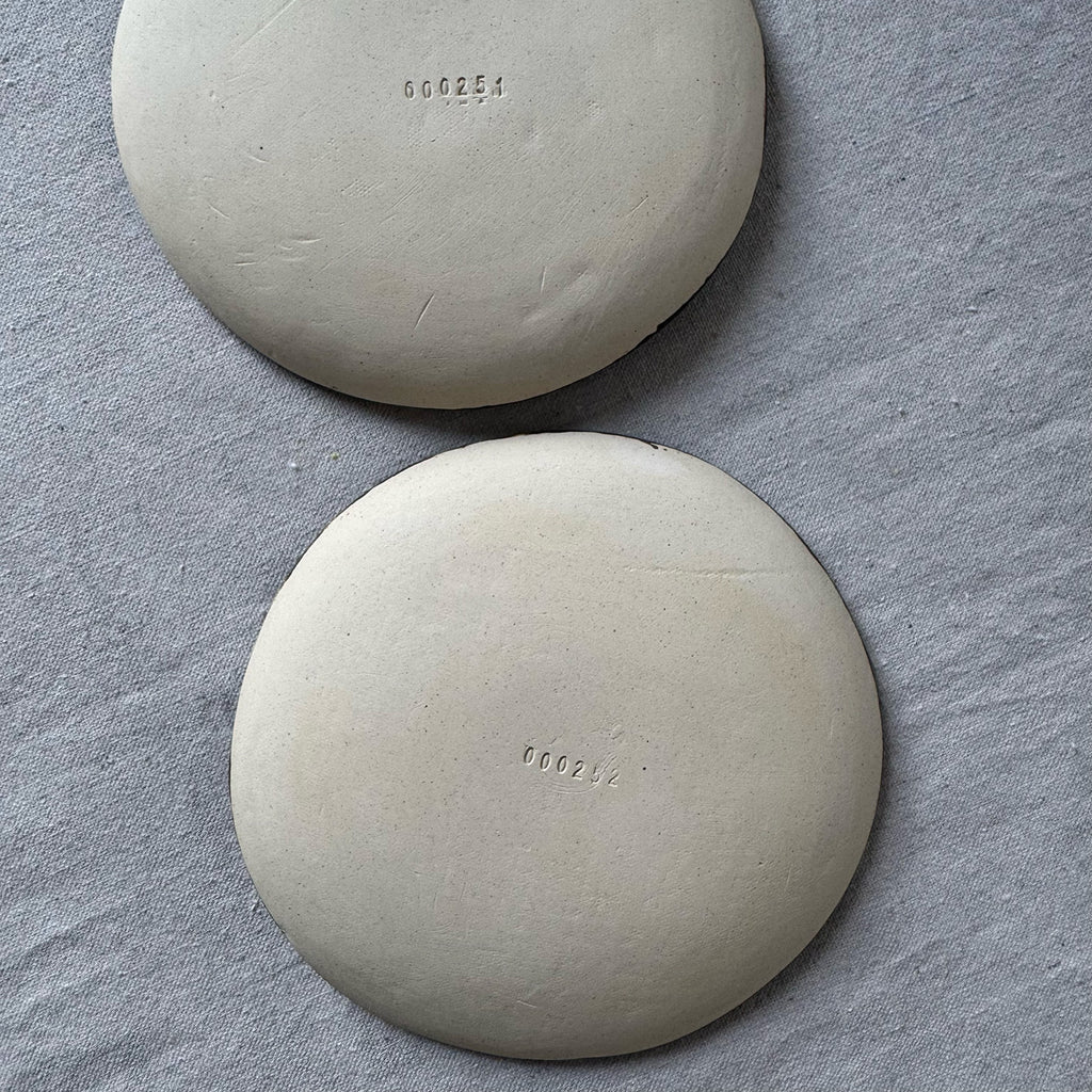 Two round plates with engraved numbers on a gray surface