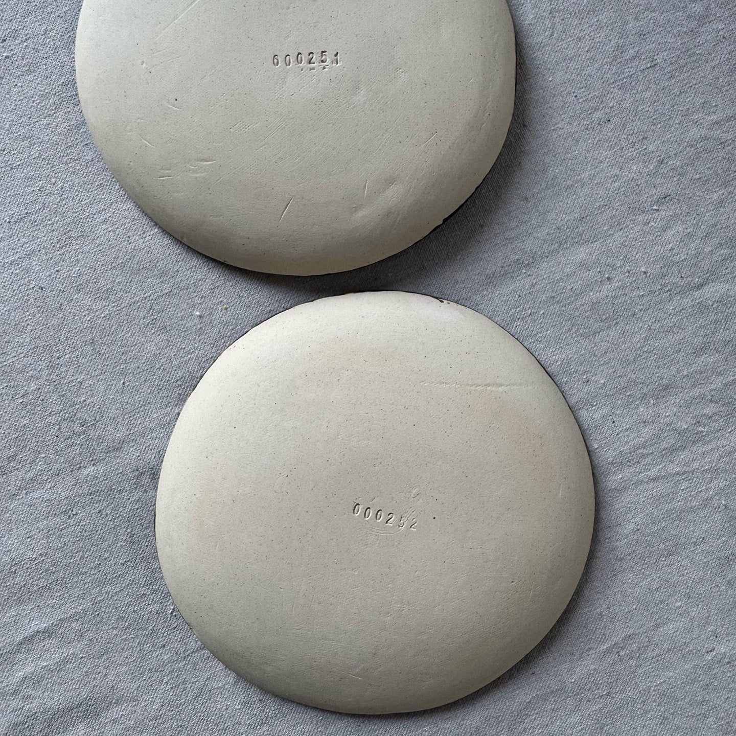 Two round plates with engraved numbers on a gray surface
