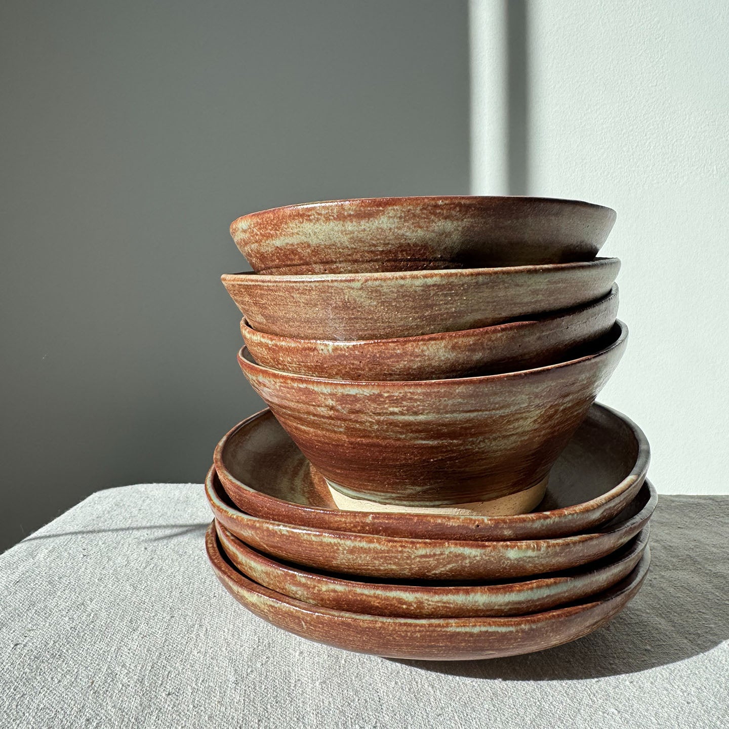 Stack of brown ceramic bowls on a light surface with a neutral background