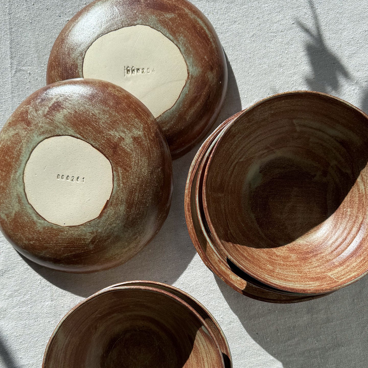 Set of ceramic bowls with brown and green glaze on a light gray surface