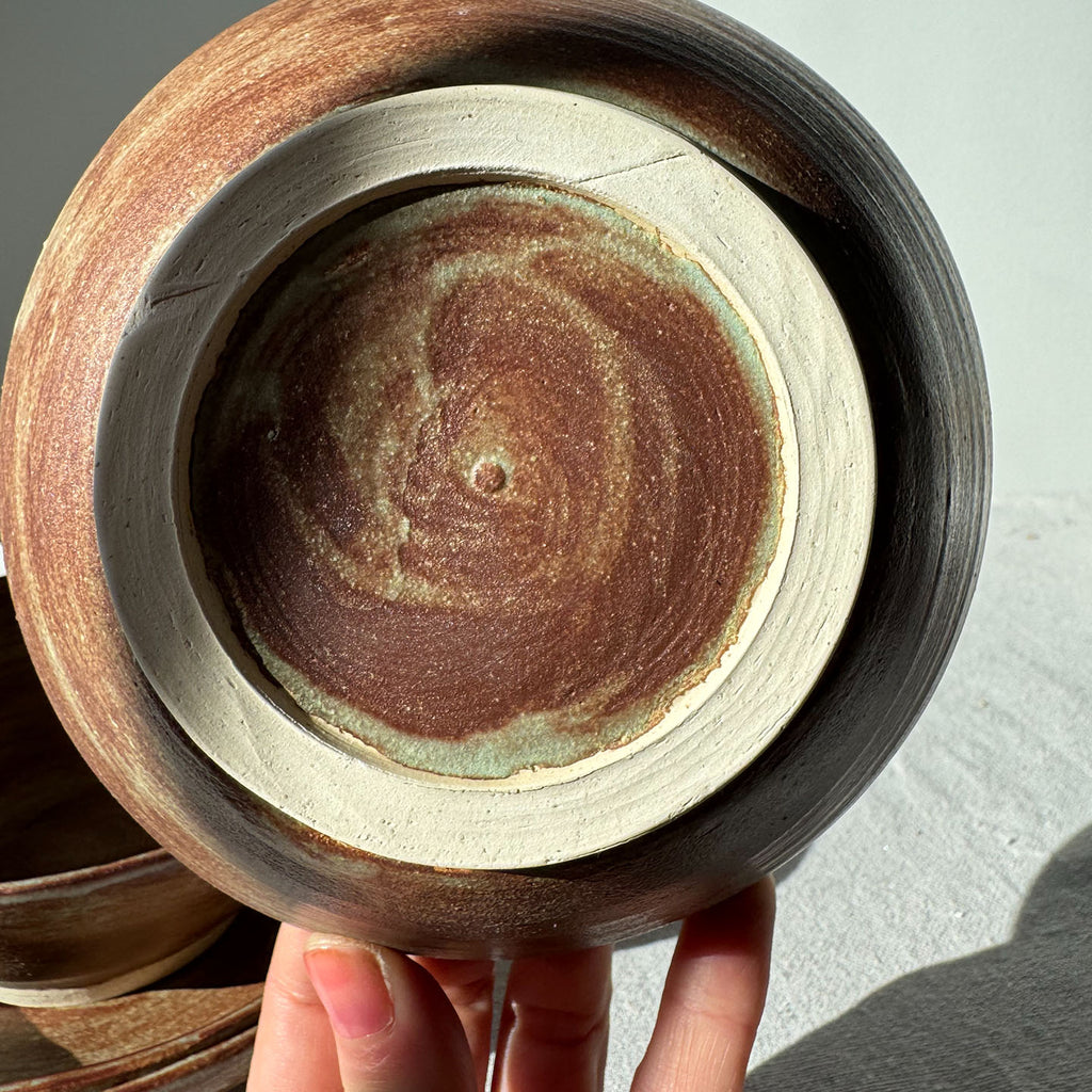 Close-up of a hand holding a ceramic pot with a textured interior.