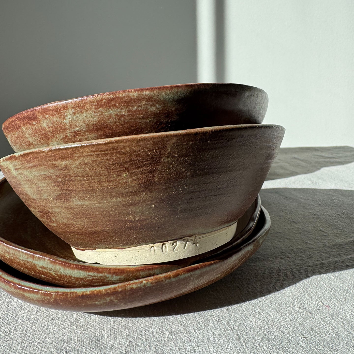 Stack of ceramic bowls with a textured surface on a light gray background