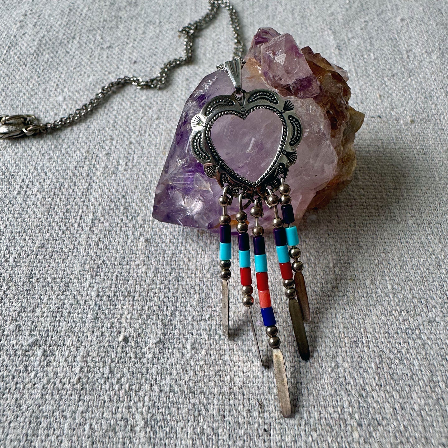 Necklace with heart-shaped pendant and beaded extensions on a crystal background