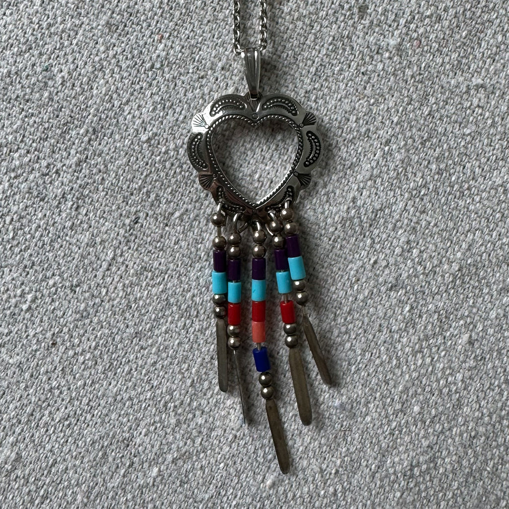 Necklace with heart-shaped pendant and colorful beads on a gray fabric background