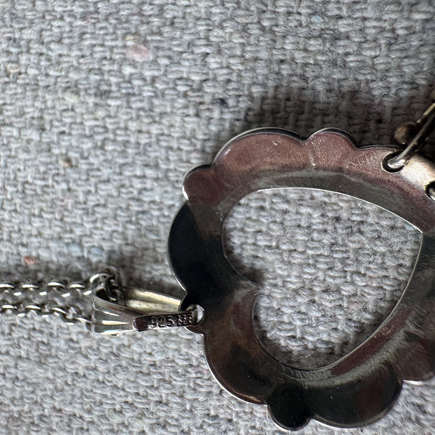 Close-up of a decorative metal object with a scalloped edge on a textured gray background